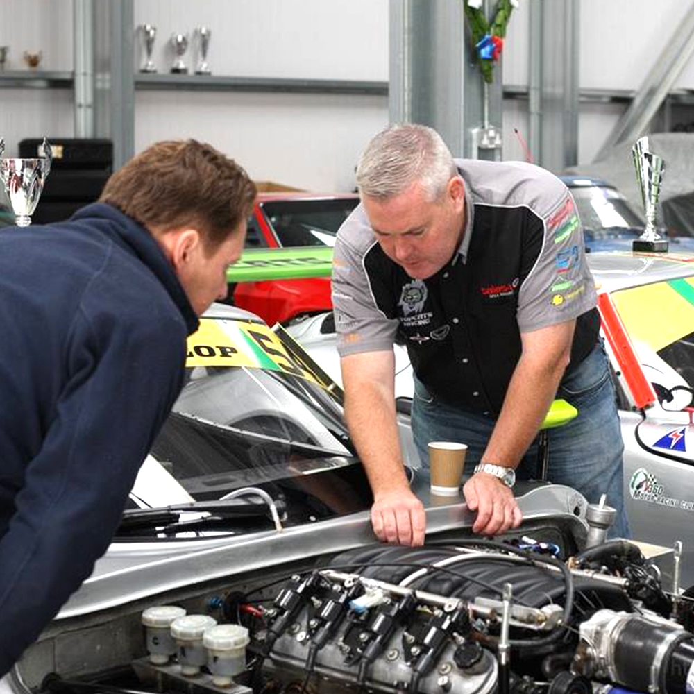 two topcats racing team members looking over and fine tuning marcos mantis engine