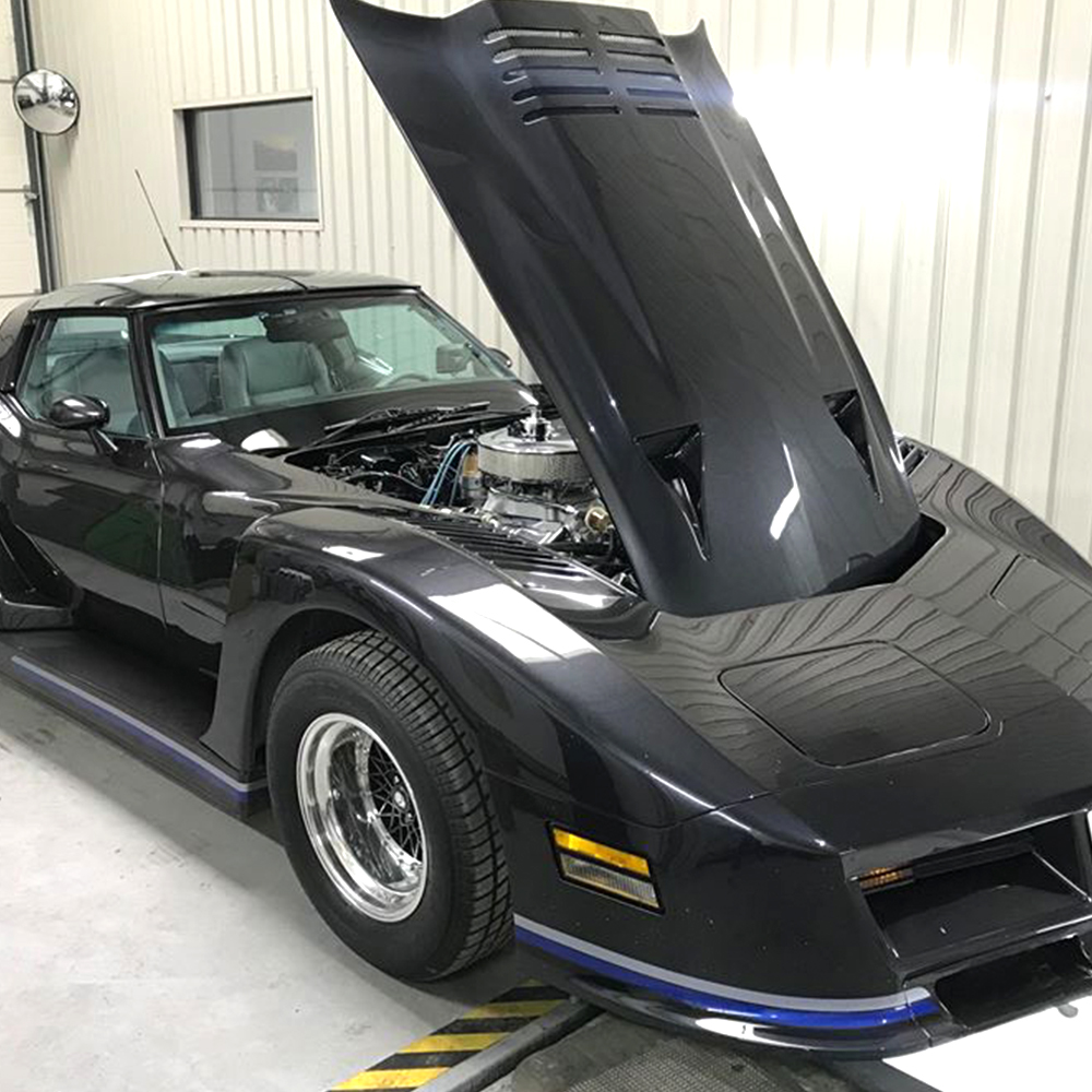 black corvette with bonnet open in topcats racing workshop