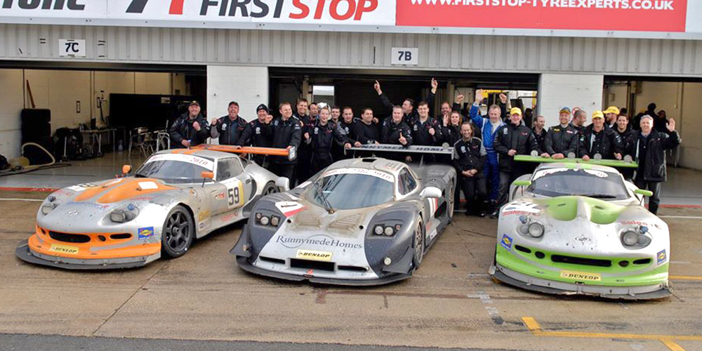 topcats racing team celebrating behind 2 marcos mantis cars and mosler mt900 at event