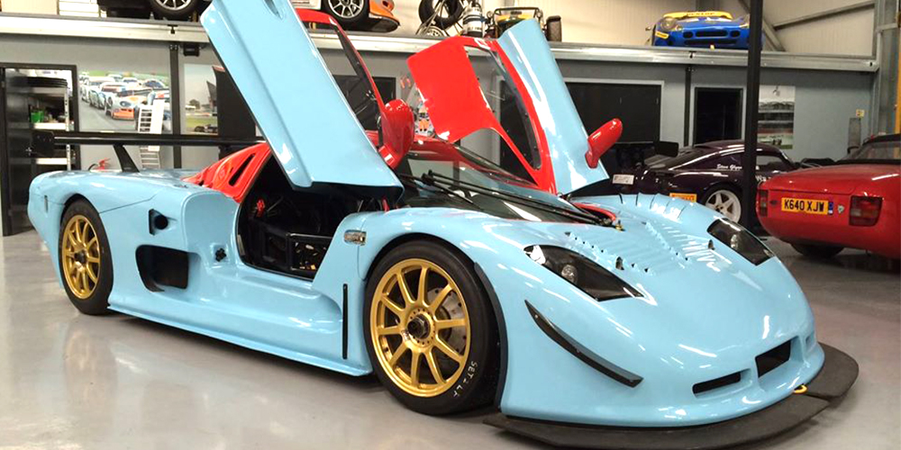 blue and red mosler mt900 with gullwing doors open on either side in topcats racing workshop